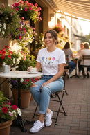 Modelo feminina camiseta branca Bloom Like a Flower café ao ar livre